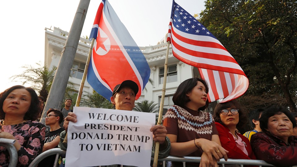 People hold North Korean and American flags near Hanoi's Metropole hotel, where Donald Trump and Kim Jong Un were meeting.