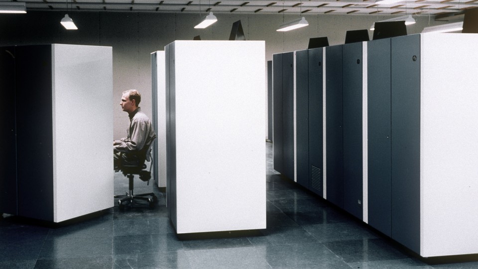 An office worker at a cubicle. He looks bored.