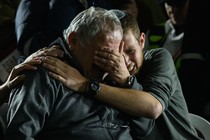 A man embraces another man as they both cry.