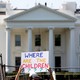 A protester holding a sign that reads "Where are the children?" in front of the White House.