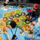 Three young men play the German board game Settlers of Catan