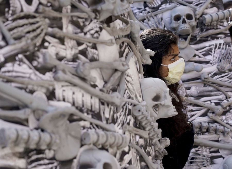 A person peers out from sculptures meant to look like large piles of human bones.