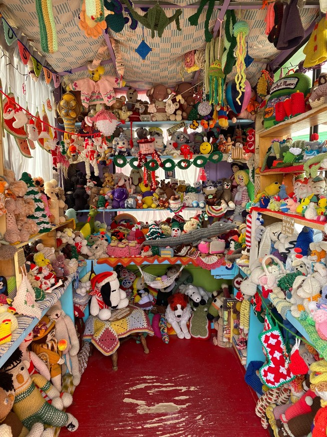 shelves filled with colorful crocheted pieces, from blankets to dolls to garlands