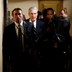 Special Counsel Robert Mueller and other officials walk down a hallway accompanied by a police officer.