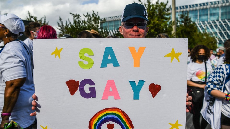 Person holding a sign with the words "SAY GAY" on it