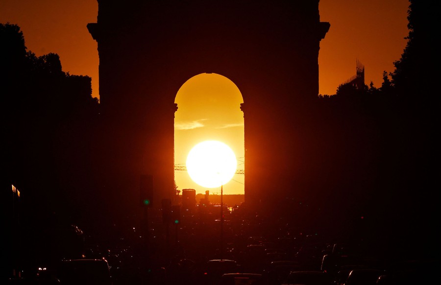 The sun sets behind a huge archway.