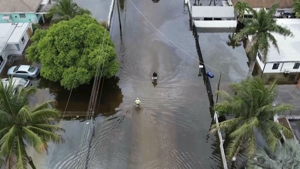 Two people make their way down a street in Miami so flooded that it's essentially a lake.