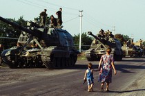 Mother and son holding hands, walking past Soviet tanks