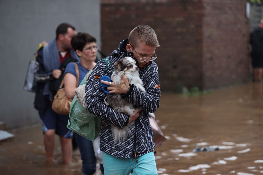 People carry belongings and pets away from floodwater.