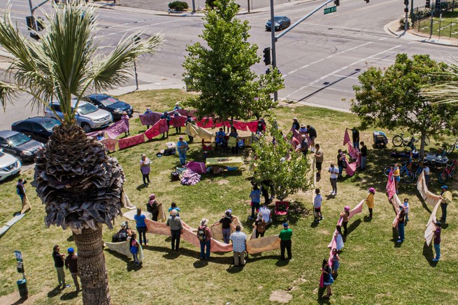 Kern County residents carrying tapestries in a circle. 