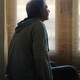 A person sits on top of a bed and gazes toward a window.