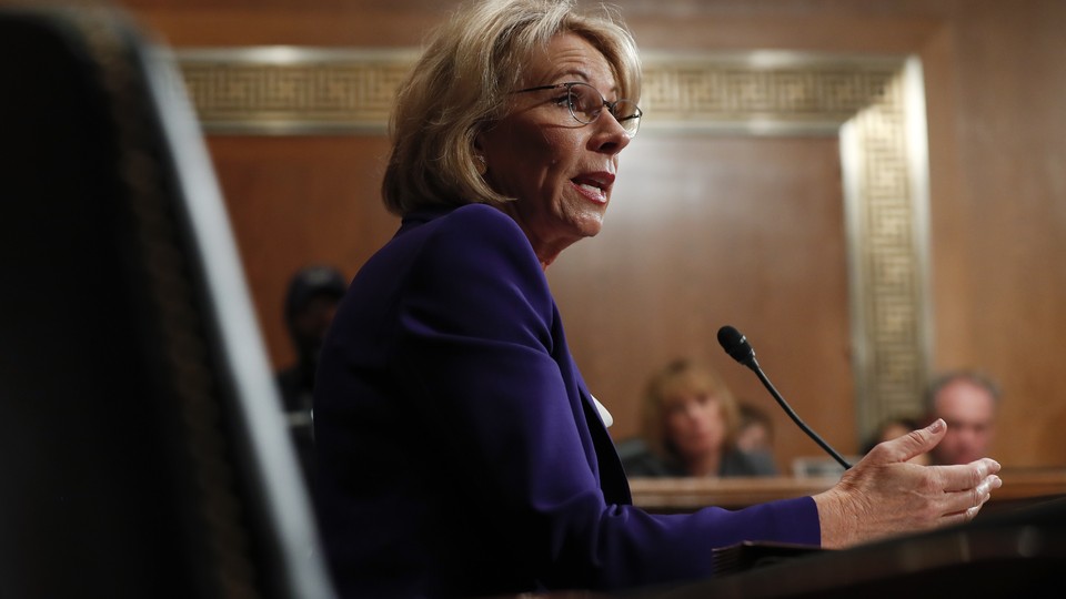 Betsy DeVos sits at a microphone during her hearing.