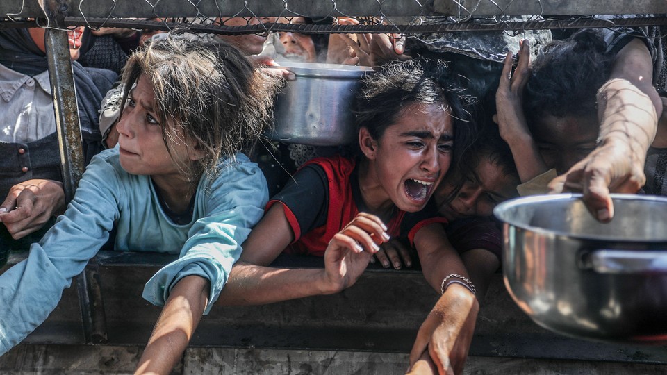 Displaced Palestinians including women and children living in tents receive food distributed by aid organizations in al Mawasi district of Khan Yunis, Gaza on May 30, 2025.