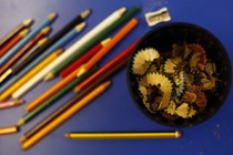 Colored pencils alongside a sharpener and a bowl of shavings