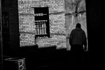 A shadowy figure walks through an alley