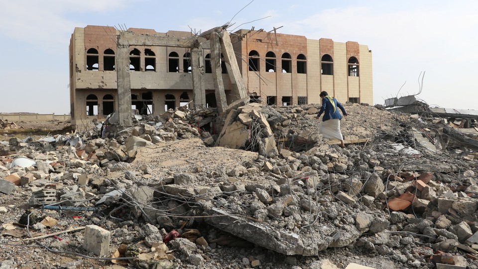 A man walks through the rubble of an air strike on a college in Saada, Yemen.