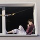A woman lounges in the window of an apartment building