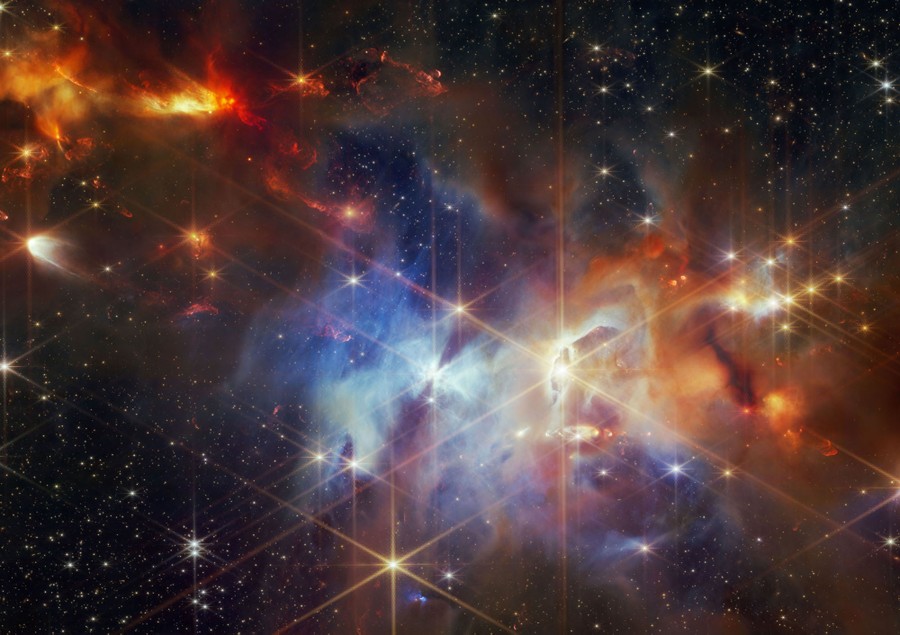 A close view of a colorful nebula, showing many clouds of gas and dust