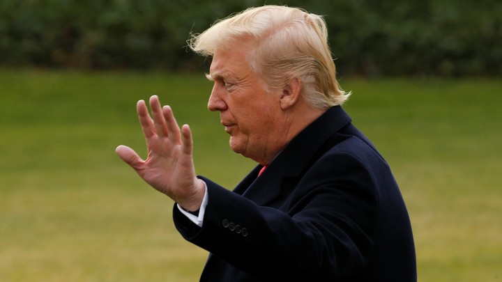 President Trump raises his hand toward a camera.