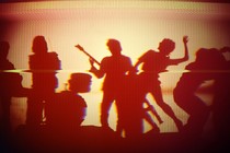 Distorted image of a rock band in silhouette, seen on a monitor