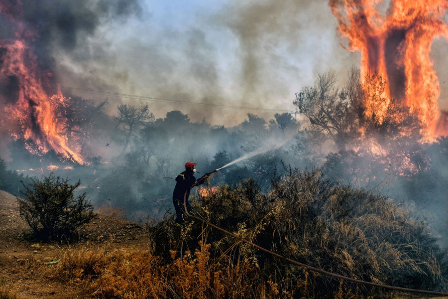 A firefighter sprays water at the flames of an approaching wildfire.