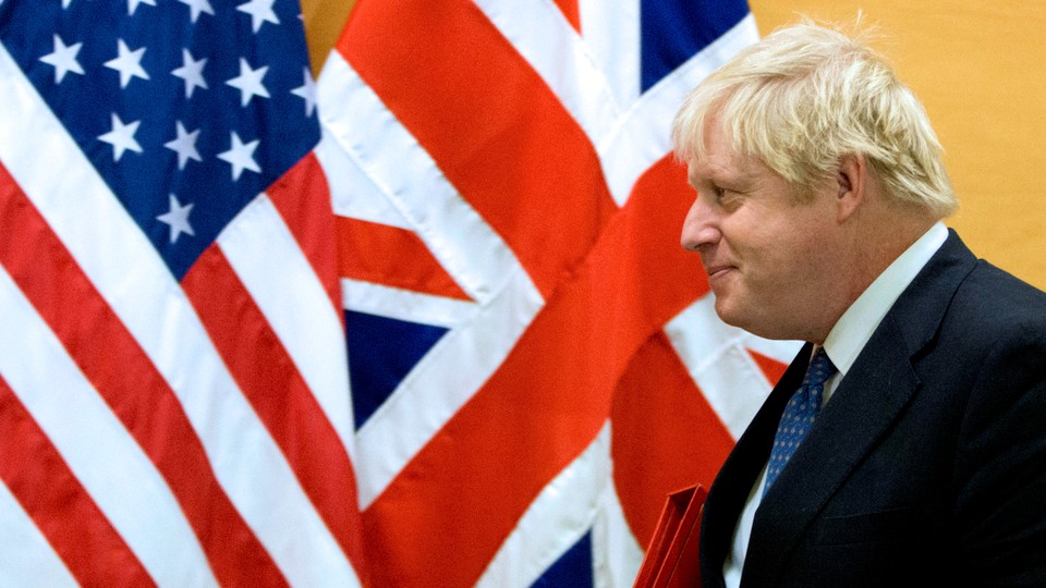 Boris Johnson walks past the flags of the United States and the United Kingdom.