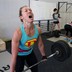 A woman makes an intense face while doing a deadlift during a CrossFit workout.