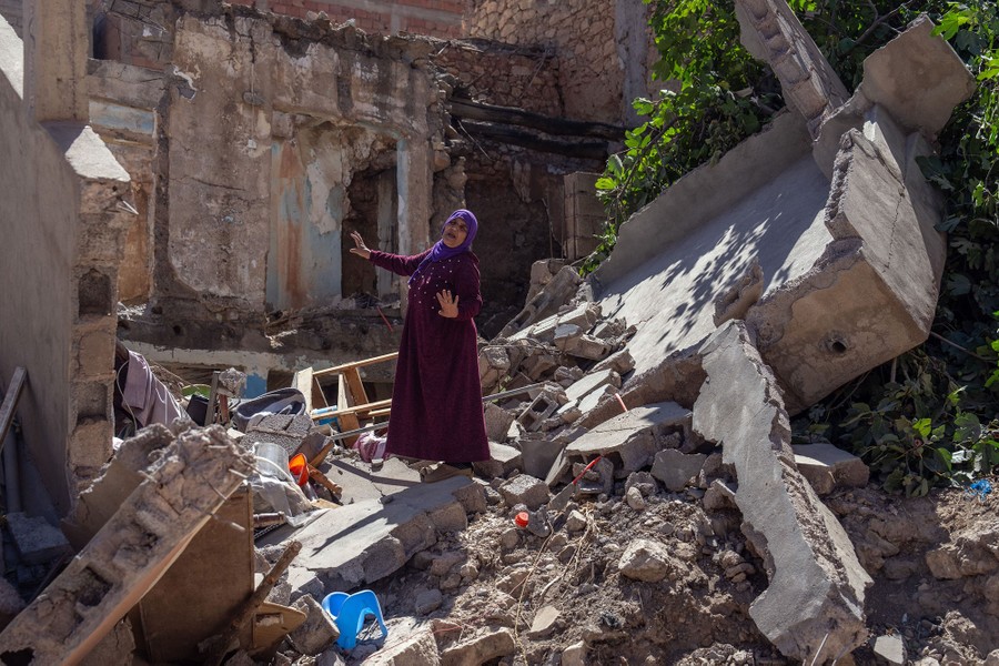 A woman gestures as she stands among the rubble of her home that was destroyed by the earthquake.