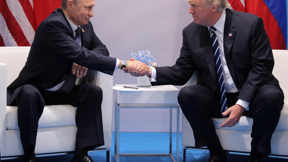 President Trump (right) and President Putin (left) sit on chairs and shake hands while answering questions during a bilateral meeting of the G20 Summit.