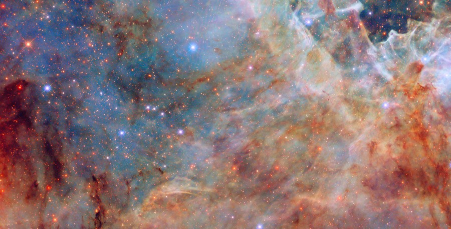 Multi-colored clouds of gas and dust surround and obscure hundreds of stars.
