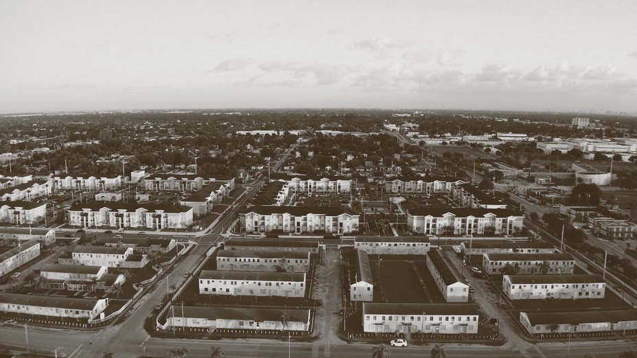 black-and-white aerial photo of neighborhood with grid of streets and white buildings with dark roofs