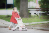 A child pushes a stroller down a street.