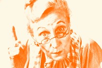 An older woman wearing glasses wags her finger