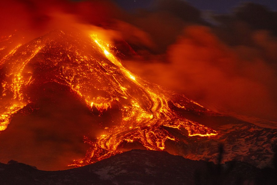 Lava flows down a slope at night.