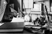 A black-and-white photo of a desk covered in personal effects