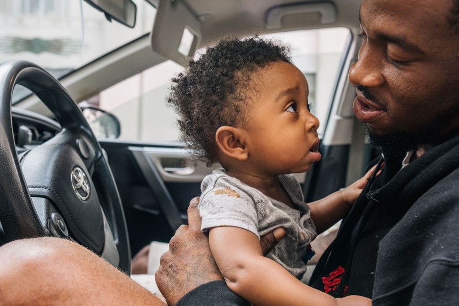 A man holds his small child inside a car.