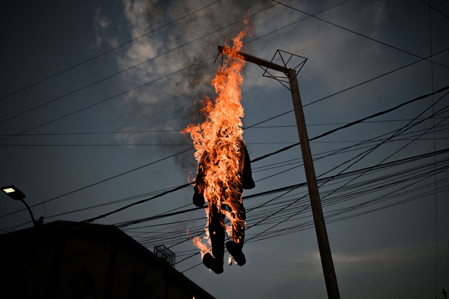 A human-size effigy of Judas burns, hanging above a street.