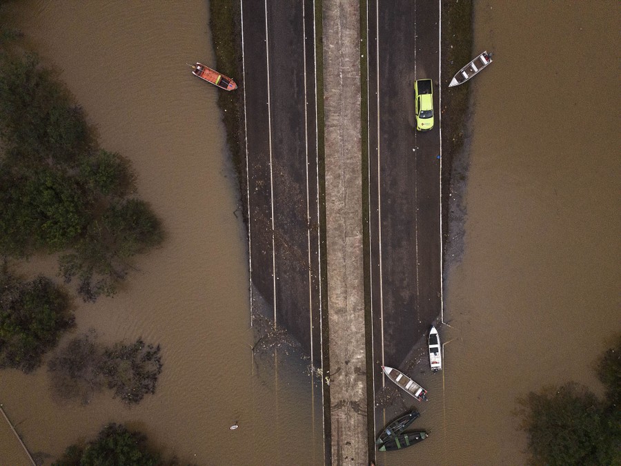 A flooded road dotted with a few boats and a truck