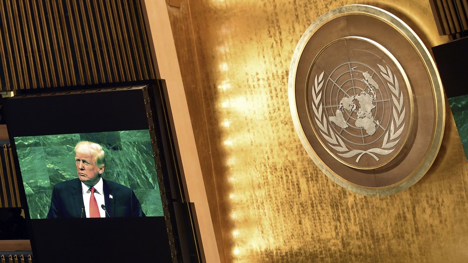 Image of Trump speaking set against a bright gold wall with a UN logo background