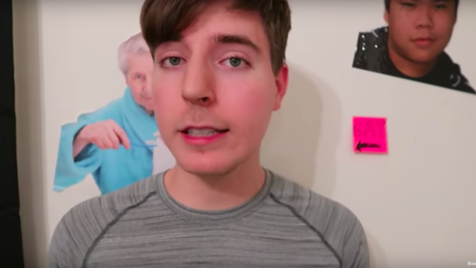 A boy looking into a camera with posters on the wall behind him