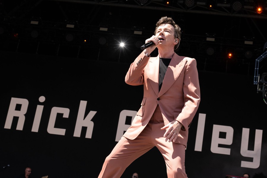A performer wearing a suit sings on stage.