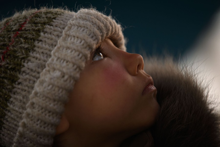 A close view of a child wearing a hat while looking up