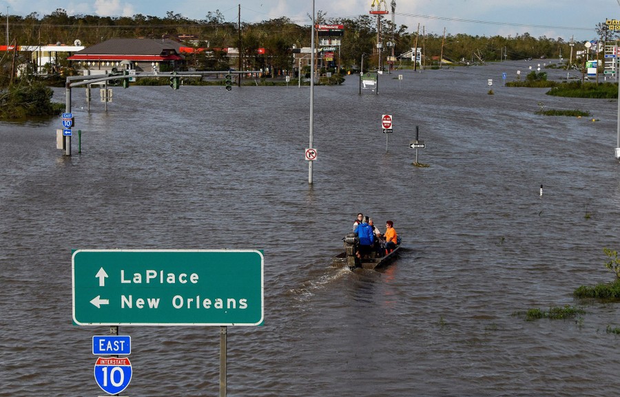 People use a boat to navigate a flooded highway.