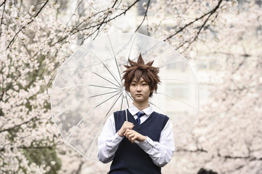 A person poses for a photo beneath blossoming trees.