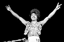 Black and white photo of Little Richard in a patterned vest and flashing peace signs