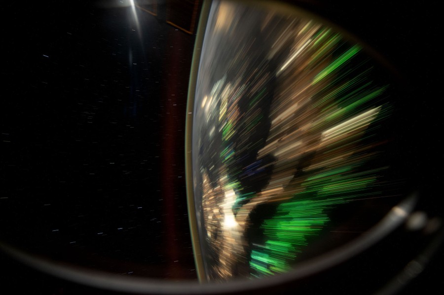 A long exposure of the lights of cities and fishing boats, showing as streaks across the rounded surface of the Earth