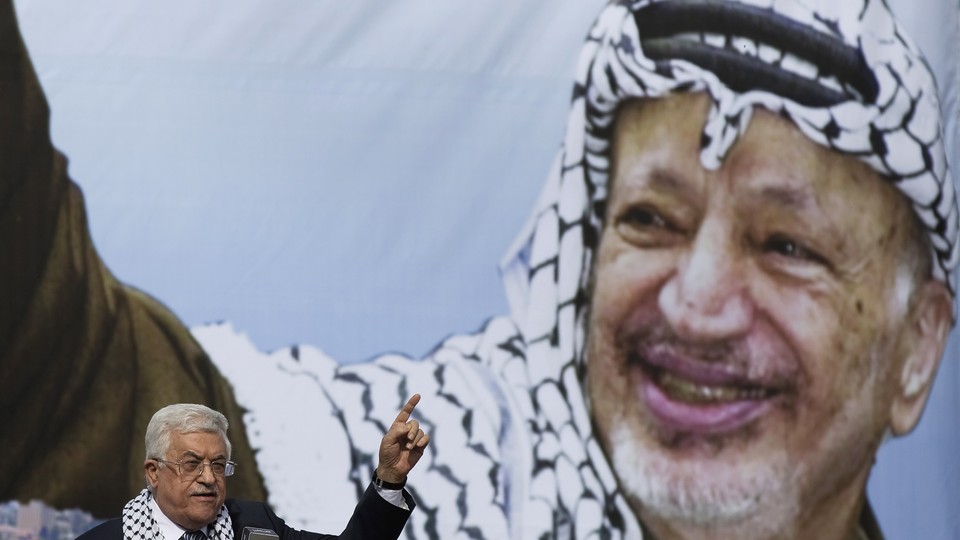 Palestinian President Mahmoud Abbas gestures beneath a poster of the late Palestinian leader Yasser Arafat, during a rally marking the anniversary of Arafat's death in Ramallah on November 11, 2014.