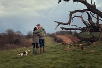 A still from the Harry and Meghan documentary showing the couple kissing in a field
