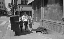 A family walks by a man laid out on the sidewalk