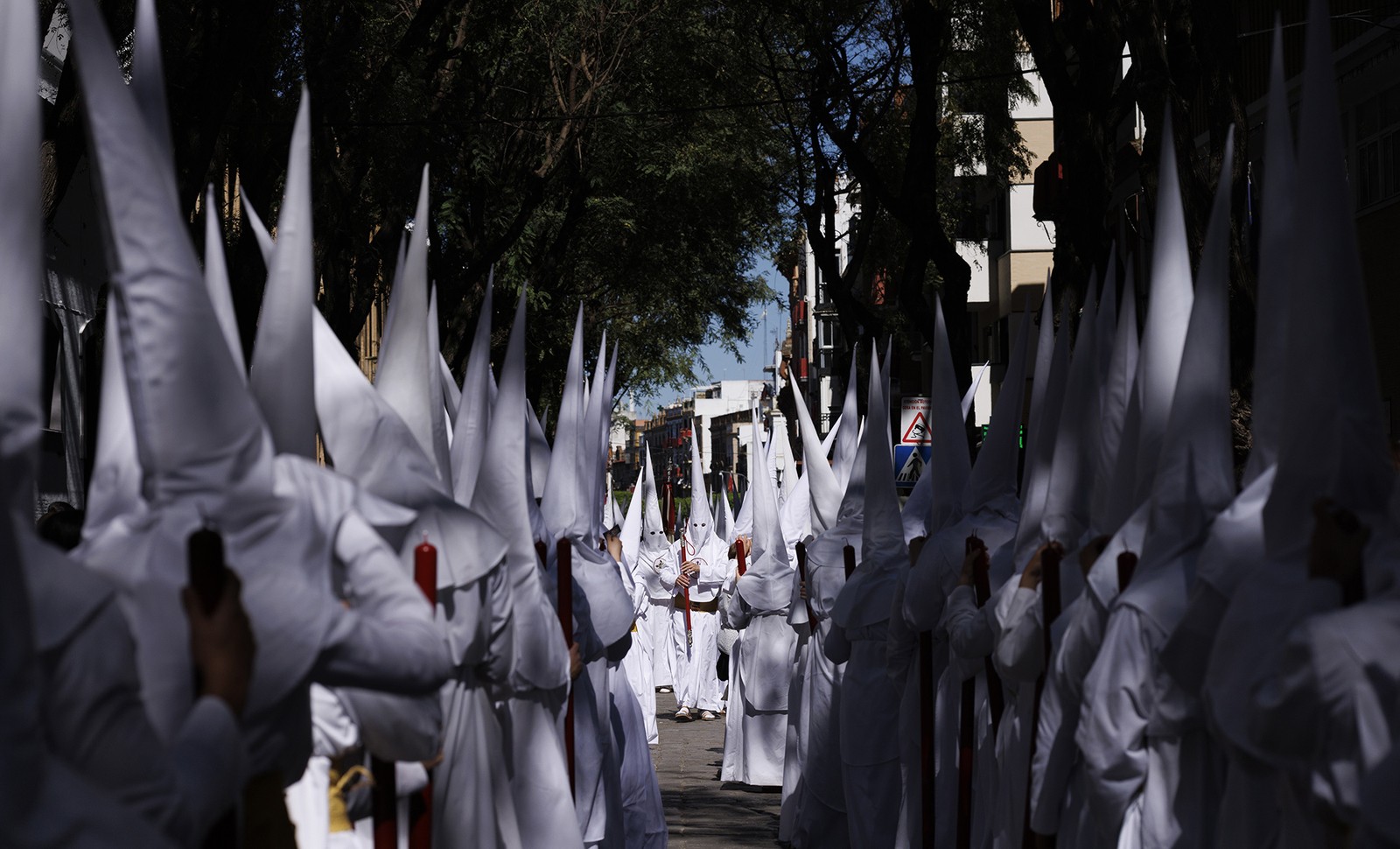 Penitents wearing pointed white hoods and robes take part in a procession during Holy Week in Spain.